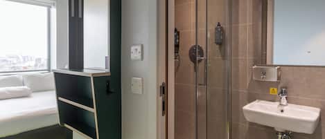 Un baño moderno con cabina de ducha de vidrio, un lavabo blanco y un estante empotrado.