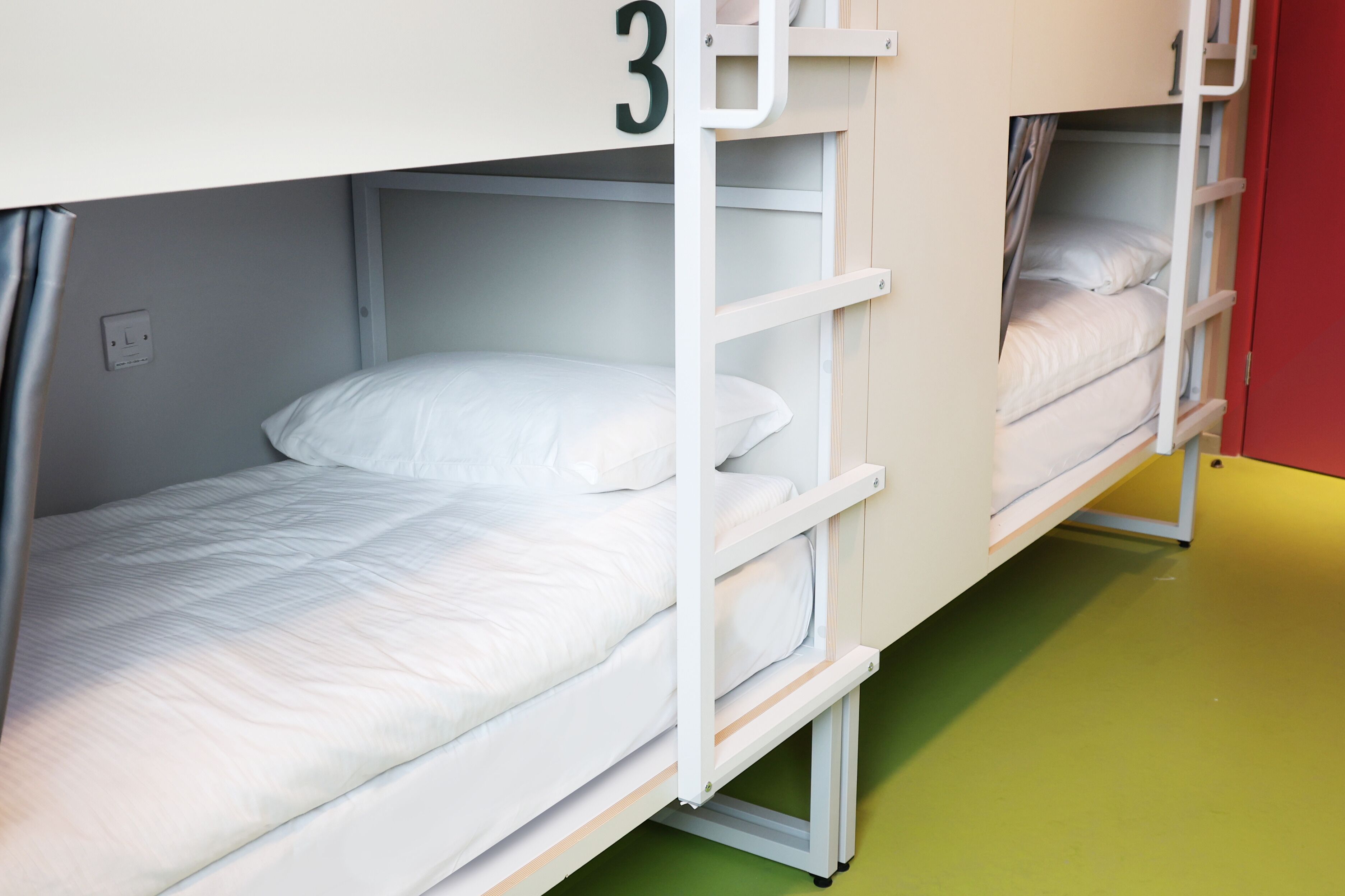 A bunk bed with a number '3' on the wall, a green floor, and a red wall.