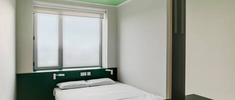Une chambre à coucher avec un lit, une fenêtre et un mur vert.