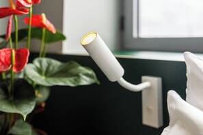 A white cylindrical object with a yellow light, attached to a wall near a window. - Clink i Lár (Dublin)