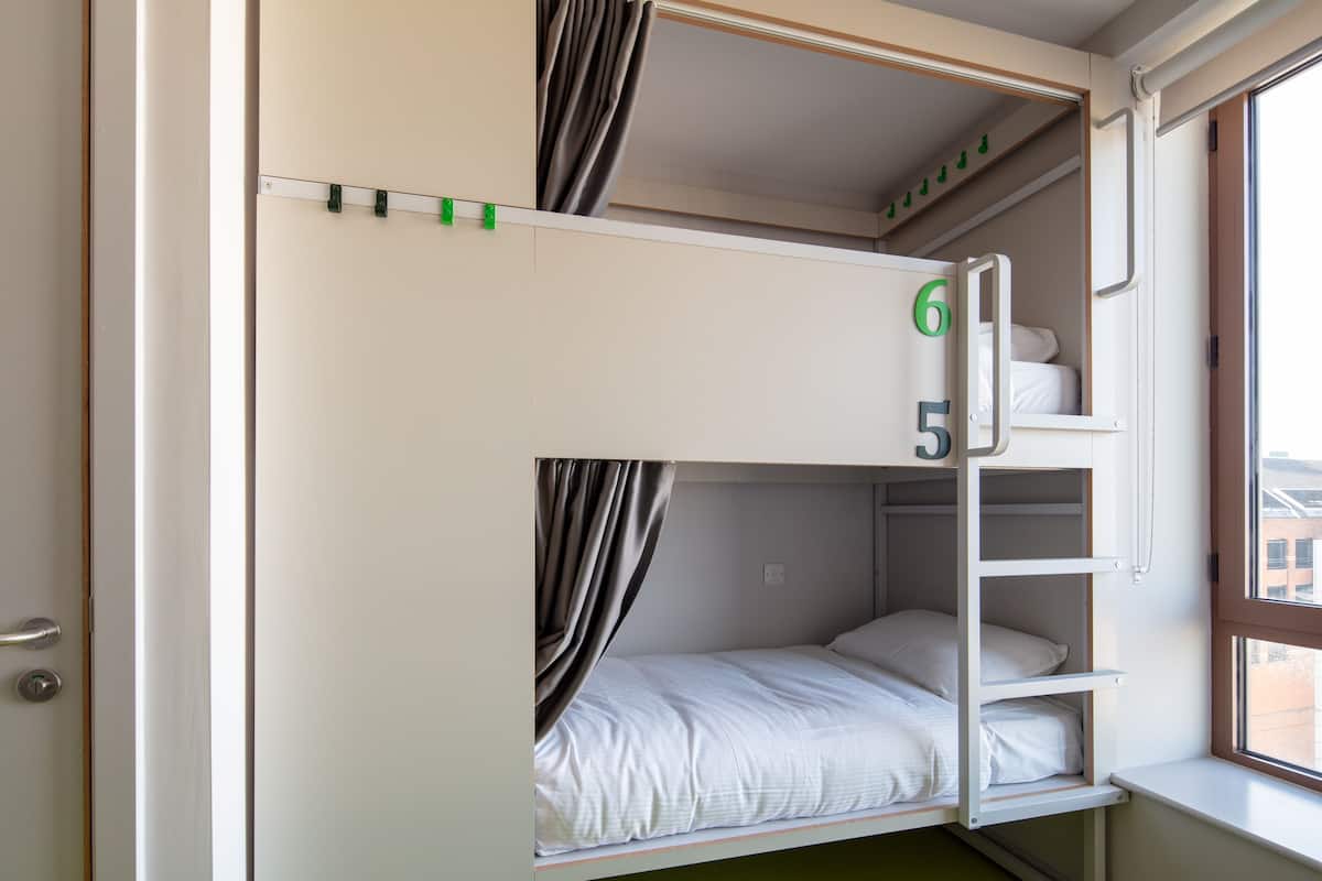 A bunk bed with numbers 5 and 6, a window with a view, and a door.