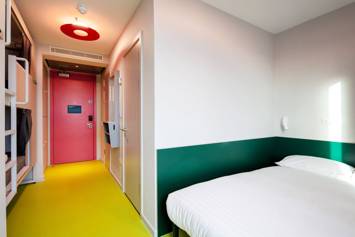 A hotel room with a bed, a wardrobe, and a bathroom.