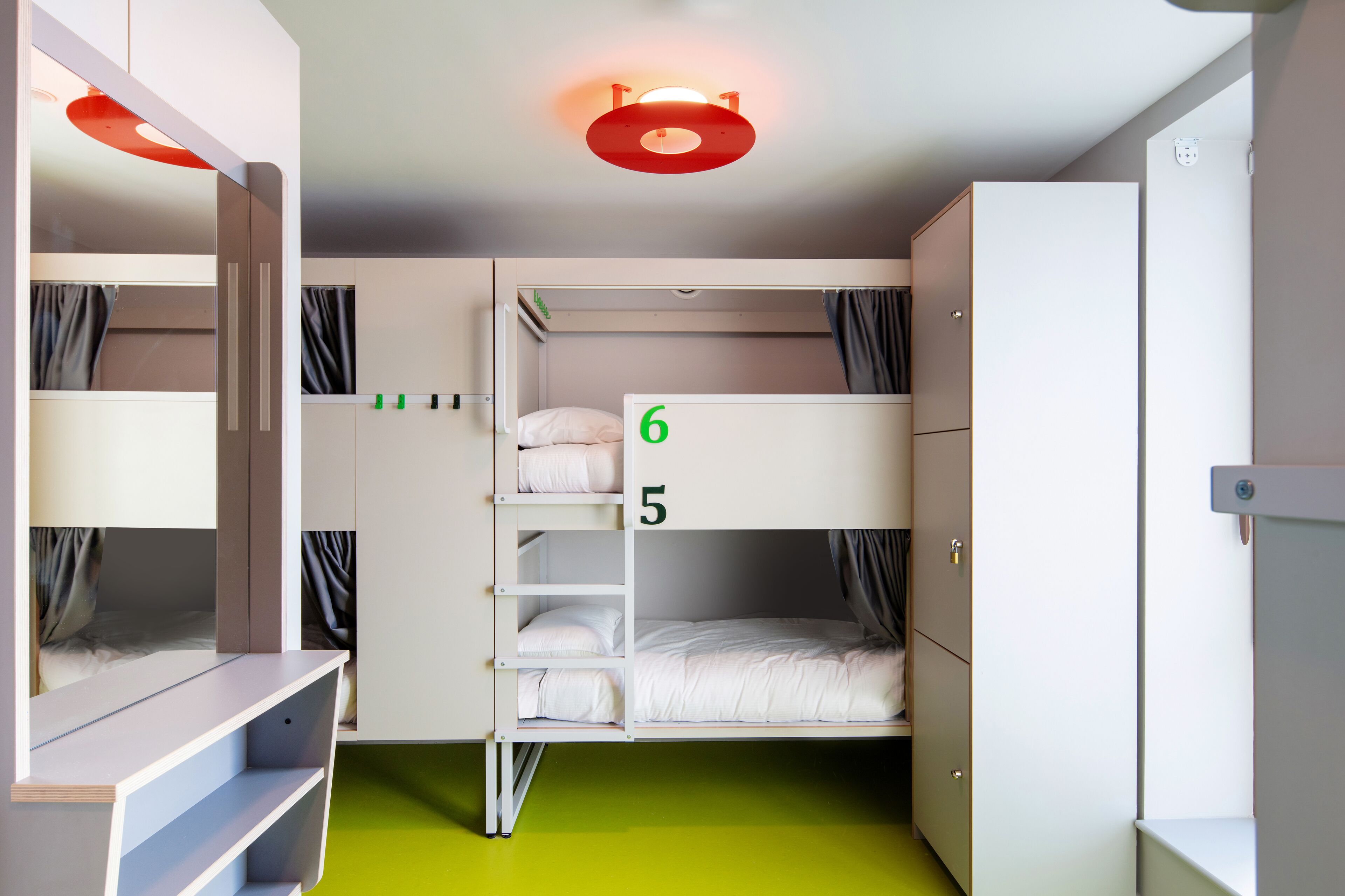 A bunk bed room with a green floor, white walls, and a ceiling light fixture.