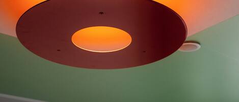 A ceiling with a circular light fixture emitting a warm glow.