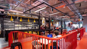 A modern bar area with seating, a staircase, and exposed ductwork. - Clink i Lár (Dublin)