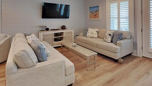 Un salon avec un canapé, une table basse, un téléviseur et une fenêtre avec des stores.