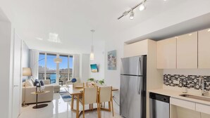Eine moderne Küche mit einem Edelstahlkühlschrank, einem Essbereich mit Tisch und Stühlen sowie einem großen Fenster mit Blick auf die Stadt.
