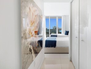 Una habitación de hotel moderna con una cama grande, vistas a la ciudad y un muro de cristal.
