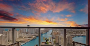 A high-rise building with a view of a river and cityscape during sunset.