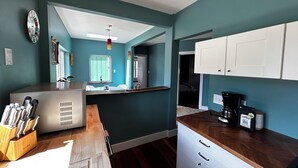 Een moderne keuken met blauwgroene wanden, witte kastjes en een houten aanrecht.