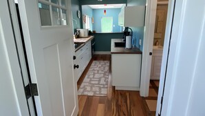 Een keuken met houten vloeren, witte kasten en een raam.
