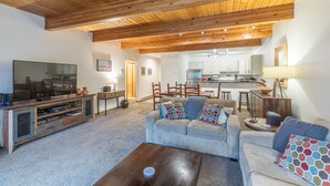 Ein geräumiges Wohnzimmer mit Holzboden, einem Fernseher, einem Sofa und einem Couchtisch.