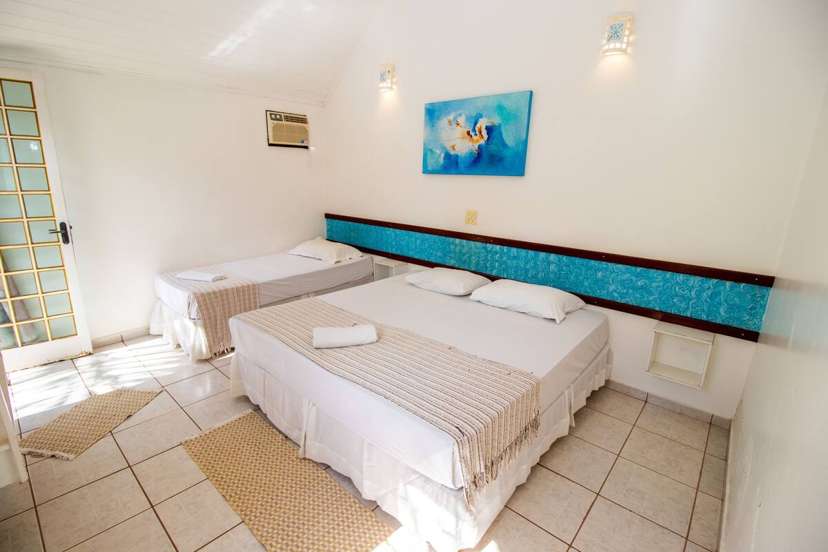 A hotel room with two beds, a large window, and a painting on the wall.