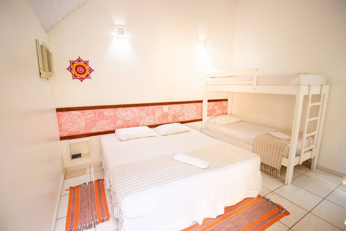 A room with a large bed, a smaller bed, a bunk bed, and a small table.