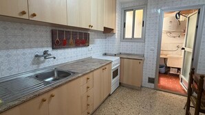 Een keuken met houten kastjes, een roestvrijstalen spoelbak, een fornuis en een raam.