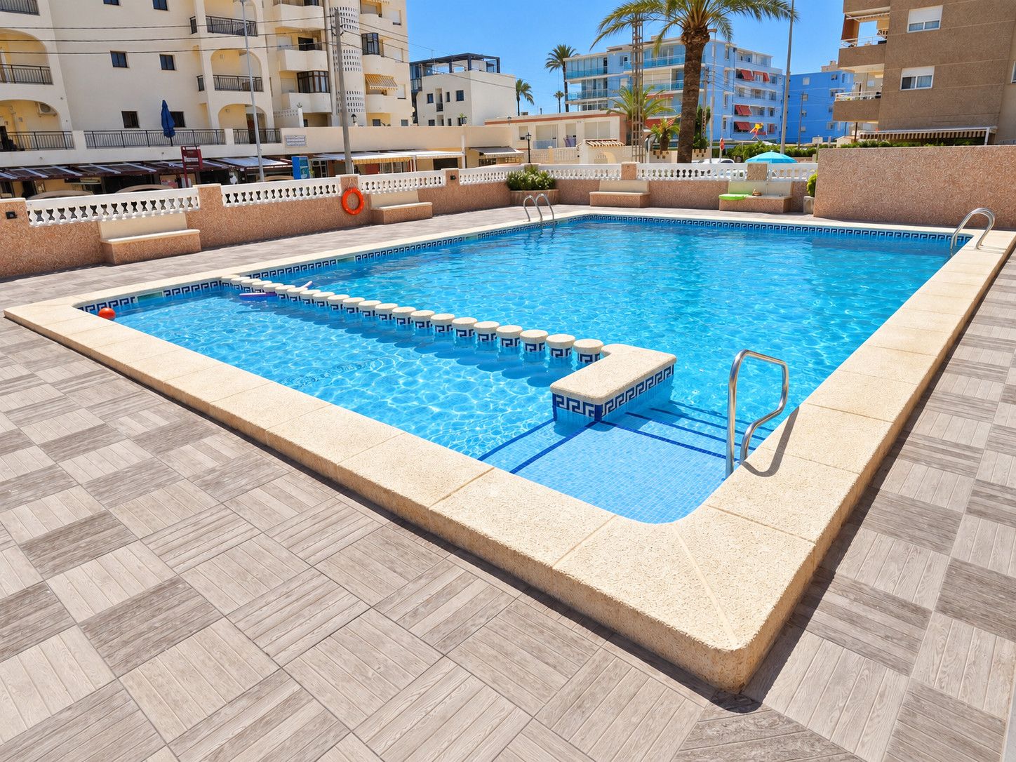 A rectangular swimming pool with a clear blue water surface, surrounded by a tiled deck.