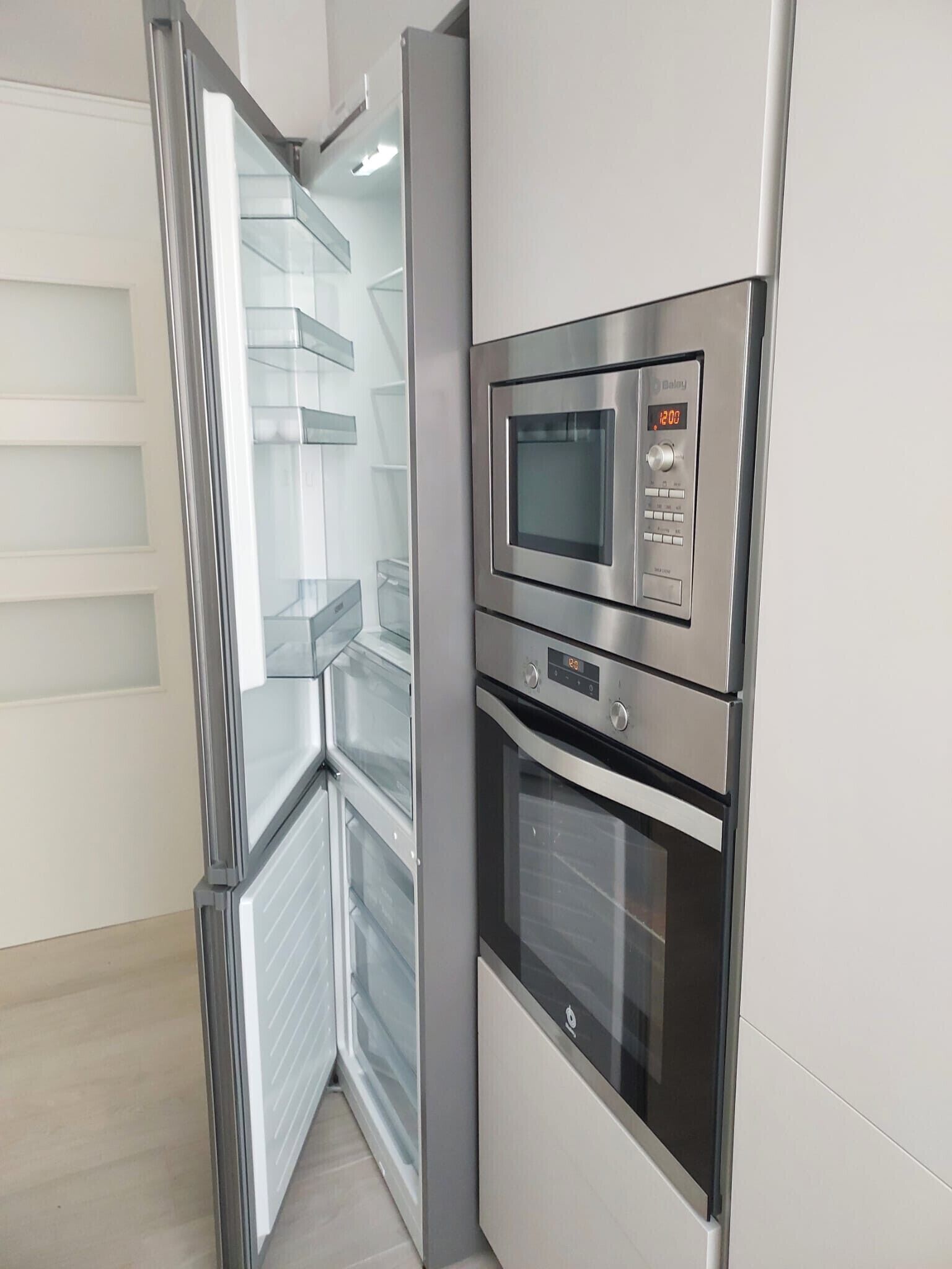 Une cuisine moderne dotée d’appareils électroménagers intégrés, notamment un four à micro-ondes, un four et un réfrigérateur.
