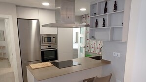 A modern kitchen with a stainless steel refrigerator, built-in oven, microwave, and a large island with bar stools.