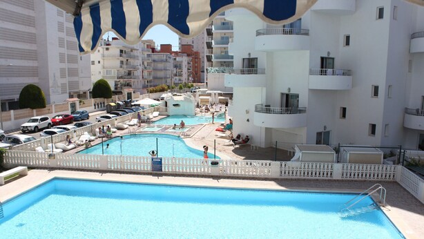 A rooftop swimming pool with multiple levels of balconies and a view of the surrounding buildings.