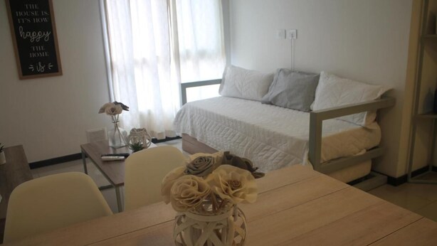A bedroom with a bed, a bedside table, a vase with flowers, and a wall with a quote. - Boulevard Illia 10C (Córdoba)
