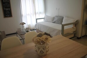 A bedroom with a bed, a bedside table, a vase with flowers, and a wall with a quote. - Boulevard Illia 10C (Córdoba)