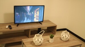 A television on a wooden stand, a remote control, and two decorative lanterns on a table. - Boulevard Illia 10C (Córdoba)