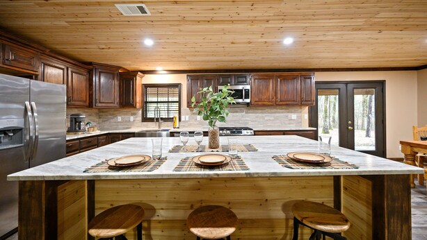 A kitchen with a large island, wooden cabinets, stainless steel appliances, and a view to the outside. - Pinot Noir 3 bedroom cabin (BROKEN BOW)