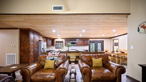 A spacious living room with leather sofas, a wooden coffee table, and a view into the kitchen area. - Pinot Noir 3 bedroom cabin (BROKEN BOW)