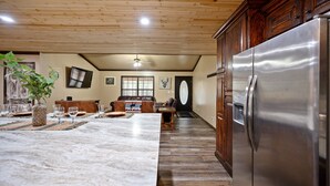 A spacious kitchen with a large island, wooden ceiling, and a stainless steel refrigerator. - Pinot Noir 3 bedroom cabin (BROKEN BOW)
