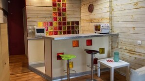 Een keuken met houten wanden, een betegelde achterwand, een magnetron, een broodrooster en twee barstoelen.
