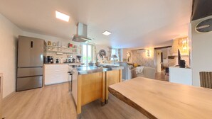 A modern kitchen with a central island, built-in appliances, and a dining area with a wooden table.