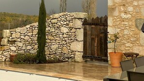 A stone building with a tiled roof, a stone wall, and a wooden gate.