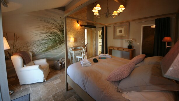 A bedroom with a bed, a chair, a desk, and a mirror.