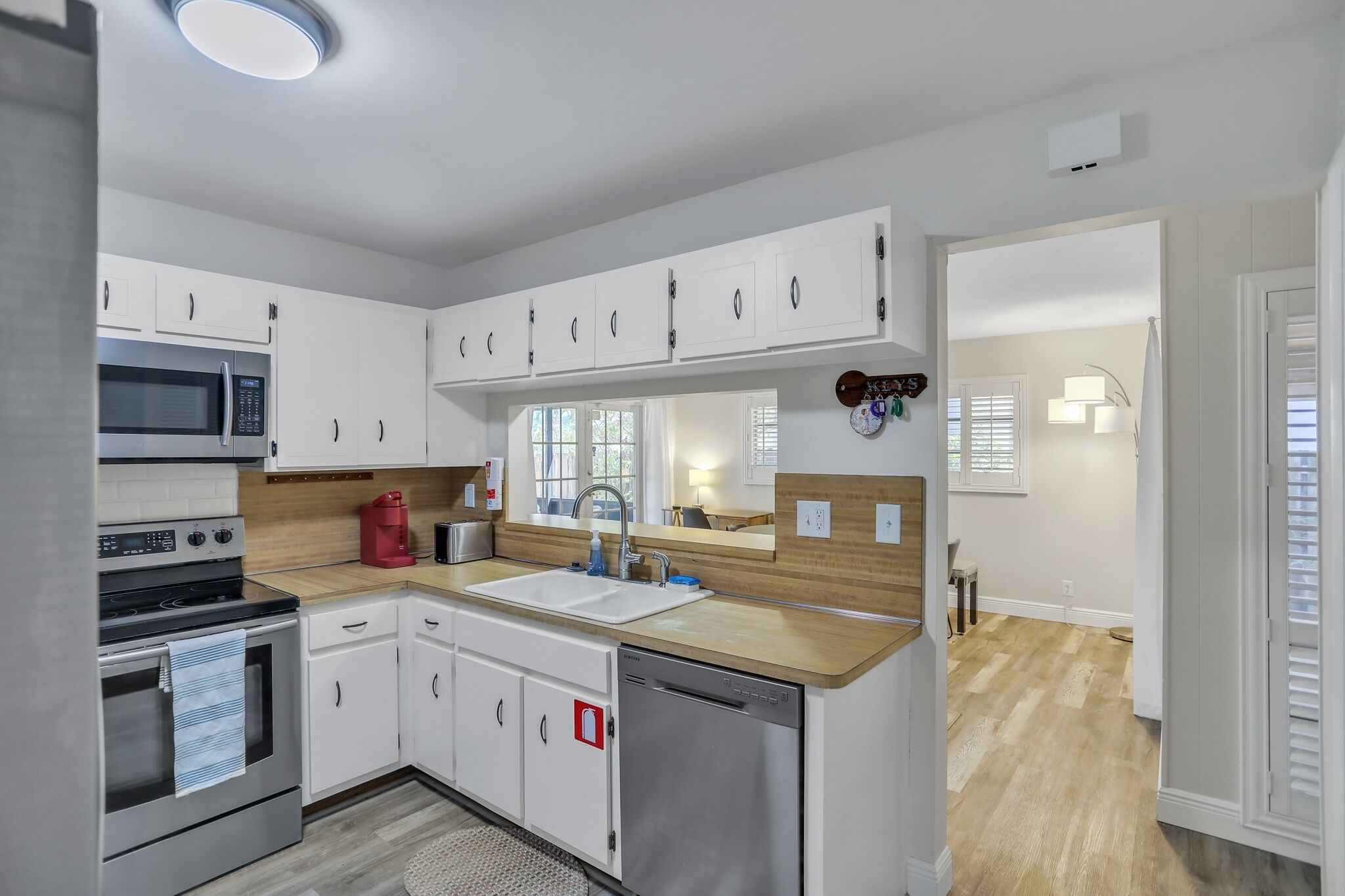 Cocina moderna con armarios blancos, electrodomésticos de acero inoxidable y encimera de madera.