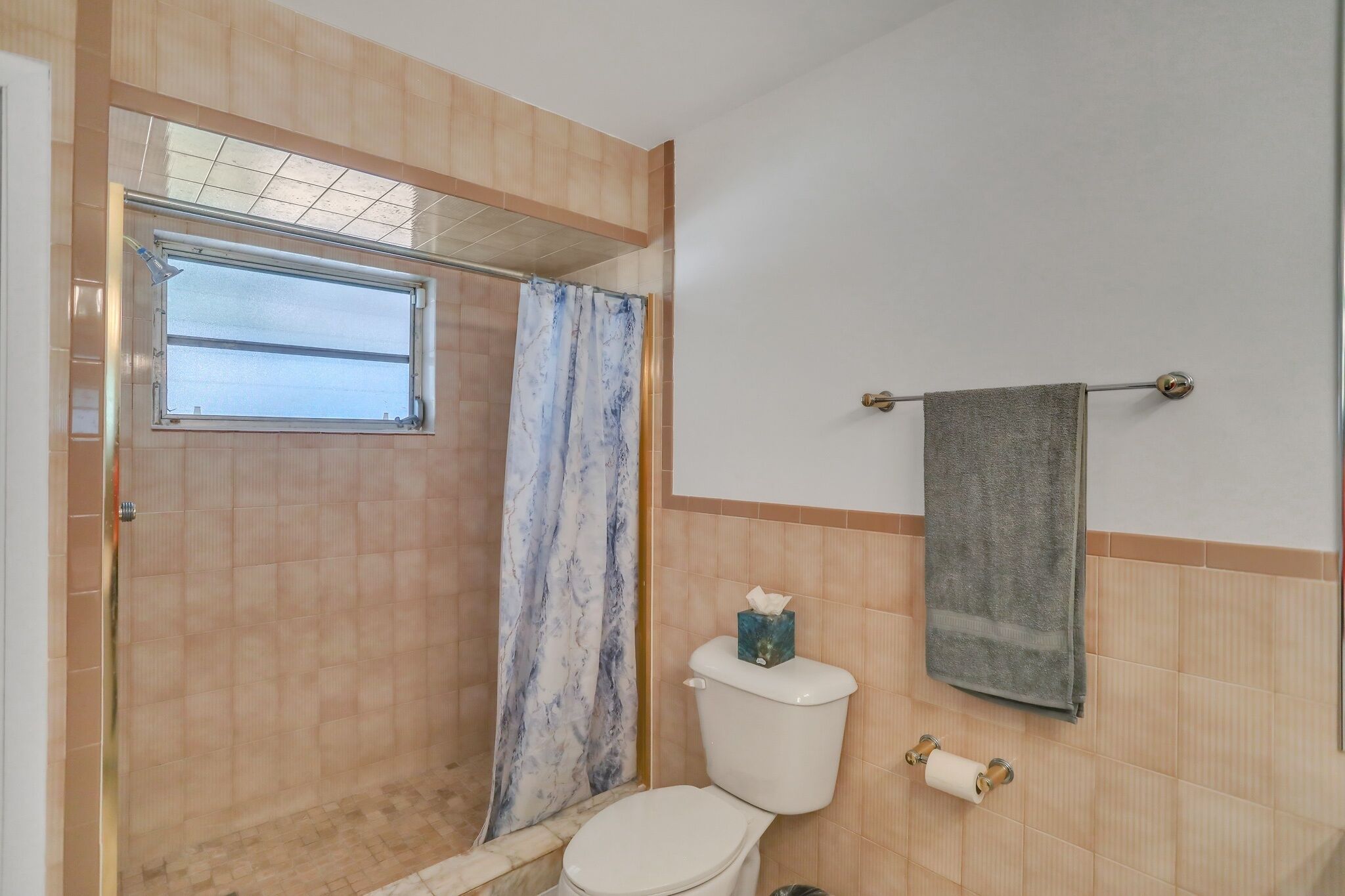 A bathroom with a shower, toilet, and a towel rack.