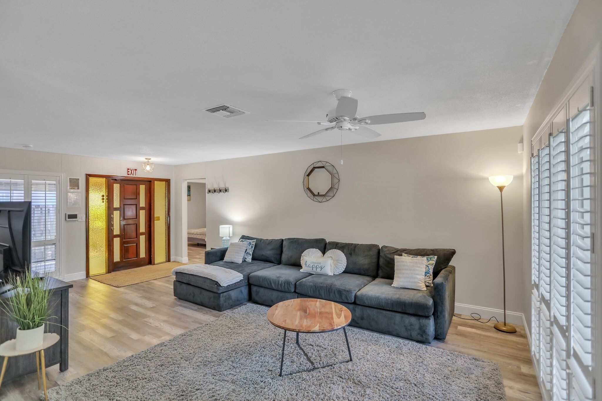 A living room with a sectional sofa, a coffee table, and a ceiling fan.