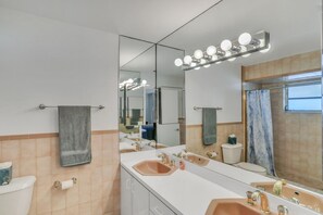 Un baño con dos lavamanos, un inodoro y un espejo grande con iluminación.