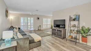 Ein modernes Wohnzimmer mit einem grauen Sofa, einem Fernseher und einem Holzkasten.
