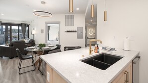 A modern kitchen with a large island, pendant lights, and a view of the city.