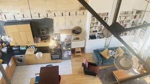 Een ruime woonkamer met een keuken, eettafel en een gezellige zithoek.