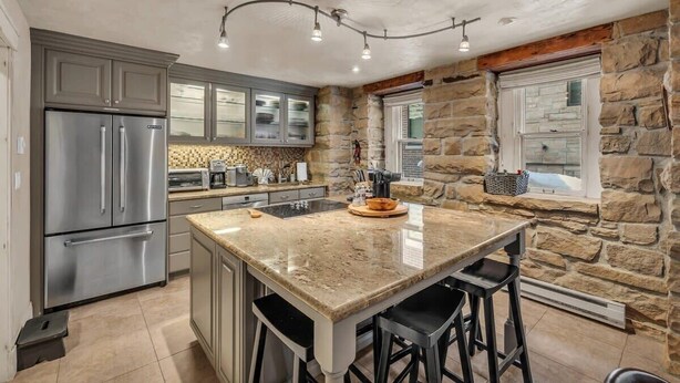 A kitchen with a granite island, stainless steel appliances, and stone walls. - Modern 2BR Steps from Main St! (Park City)