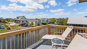 A wooden deck with a glass balustrade overlooking a river, surrounded by houses and trees. - New Beginnings: Fisherman's Paradise | Boat Dock (Nags Head)
