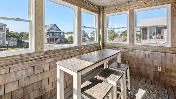 A room with a wooden bench, large windows, and a view of neighboring houses. - New Beginnings: Fisherman's Paradise | Boat Dock (Nags Head)