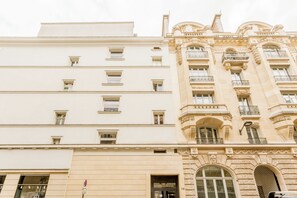 A multi-story building with a classical architectural style, featuring ornate balconies and large windows. - Merveil - Luxury Suite -Opera - Volney II (Paris)