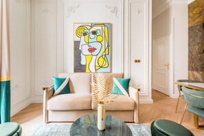 Una sala de estar moderna con un sofá color beige, una mesa de centro de vidrio y un cuadro sobre ella.