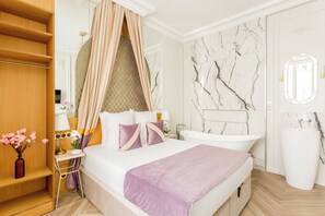 A bedroom with a canopy bed, a vanity with a mirror, and a bathtub. - Merveil - Luxury Suite -Opera - Volney II (Paris)