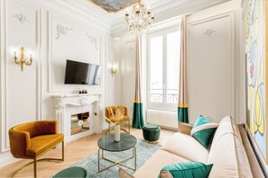 Una sala de estar con chimenea, televisor, sofá y candelabro.