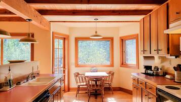 Una cocina con armarios de madera, una mesa de comedor y una ventana con vista a árboles.