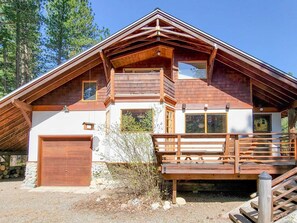 A wooden cabin with a balcony, a garage, and a deck.