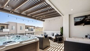 Une terrasse sur le toit avec un jacuzzi, des sièges d’extérieur et un téléviseur fixé au mur.